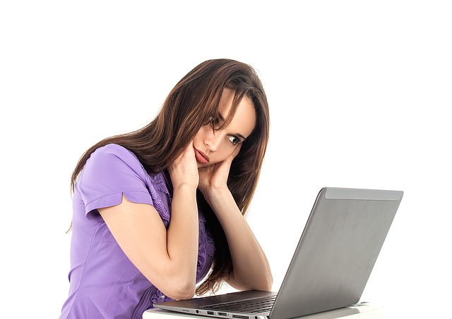 a young woman looks frustrated as she looks at her laptop