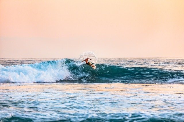 Surfer riding wave with sunset colors