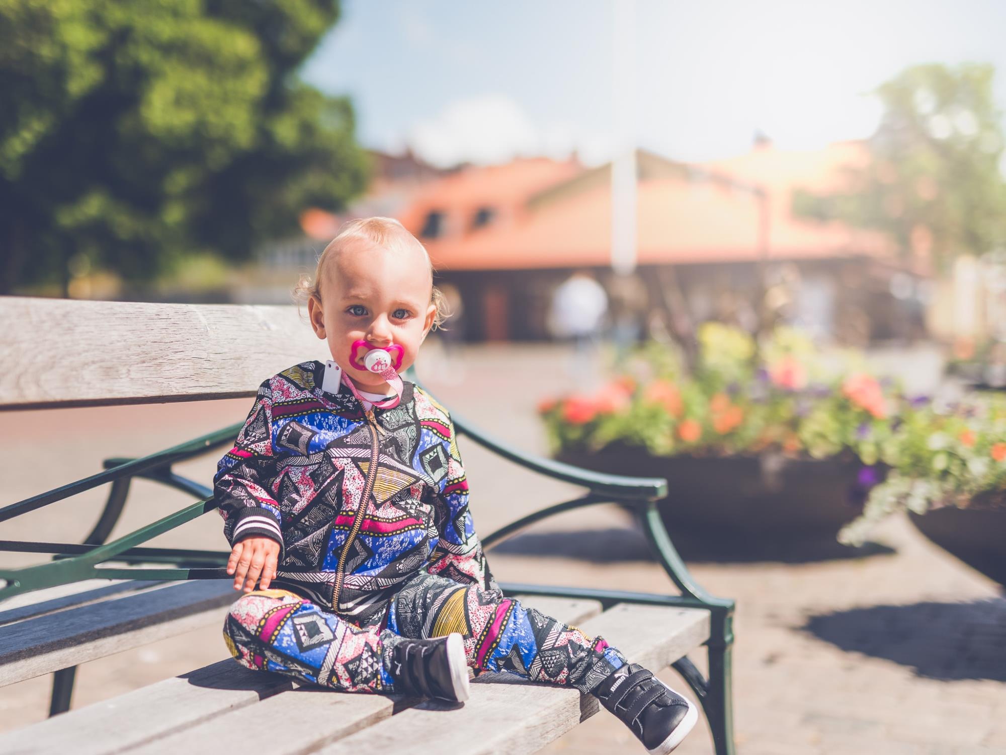 baby sitting on a bench in a park