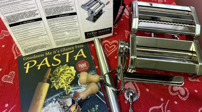 Pasta making kit with cookbook, pasta maker, instructions, on a table.