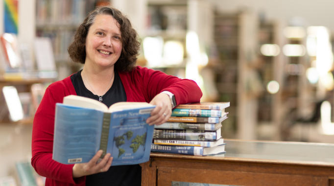 Branch manager Mellisa Hannum holding open book in library.