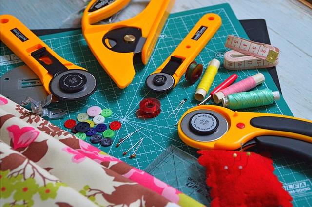 tools for quilting on top of a cutting pad next to fabric squares.