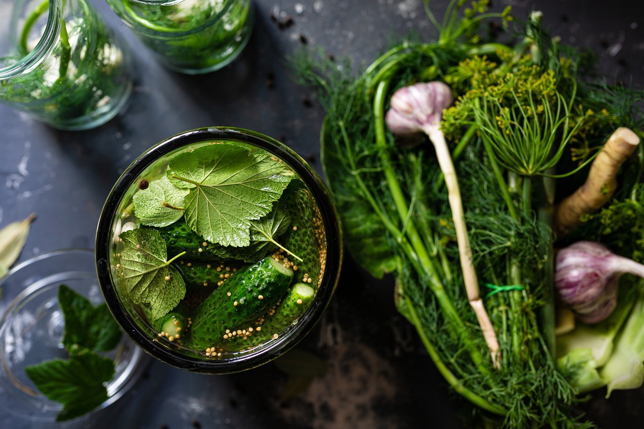 A jar with pickles, grape leaves, garlic, dill, and spices.